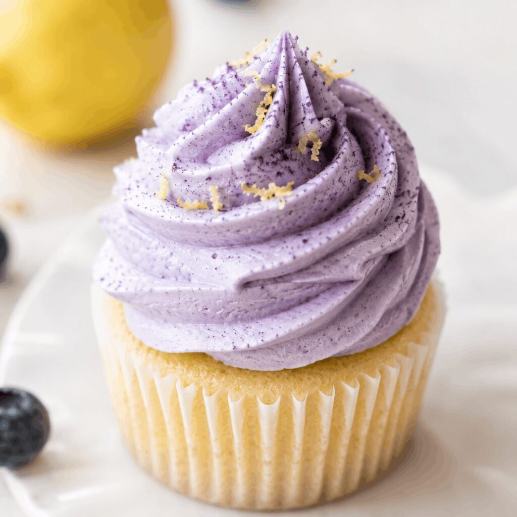 Gros plan d’un cupcake garni de ganache montée au bleuet et de zestes de citron